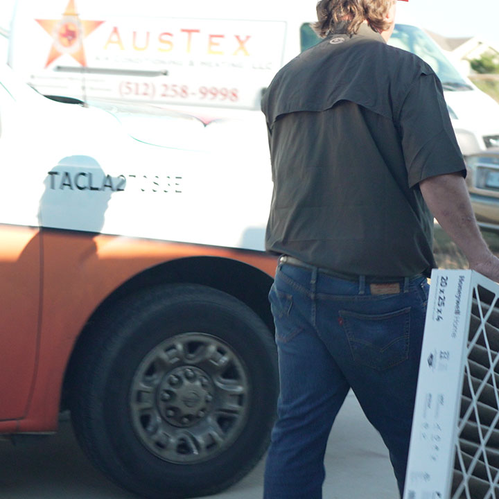 HVAC technician servicing outdoor air conditioning unit at residential home
