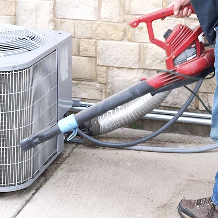 HVAC technician cleaning outdoor air conditioning condenser coil for better efficiency
